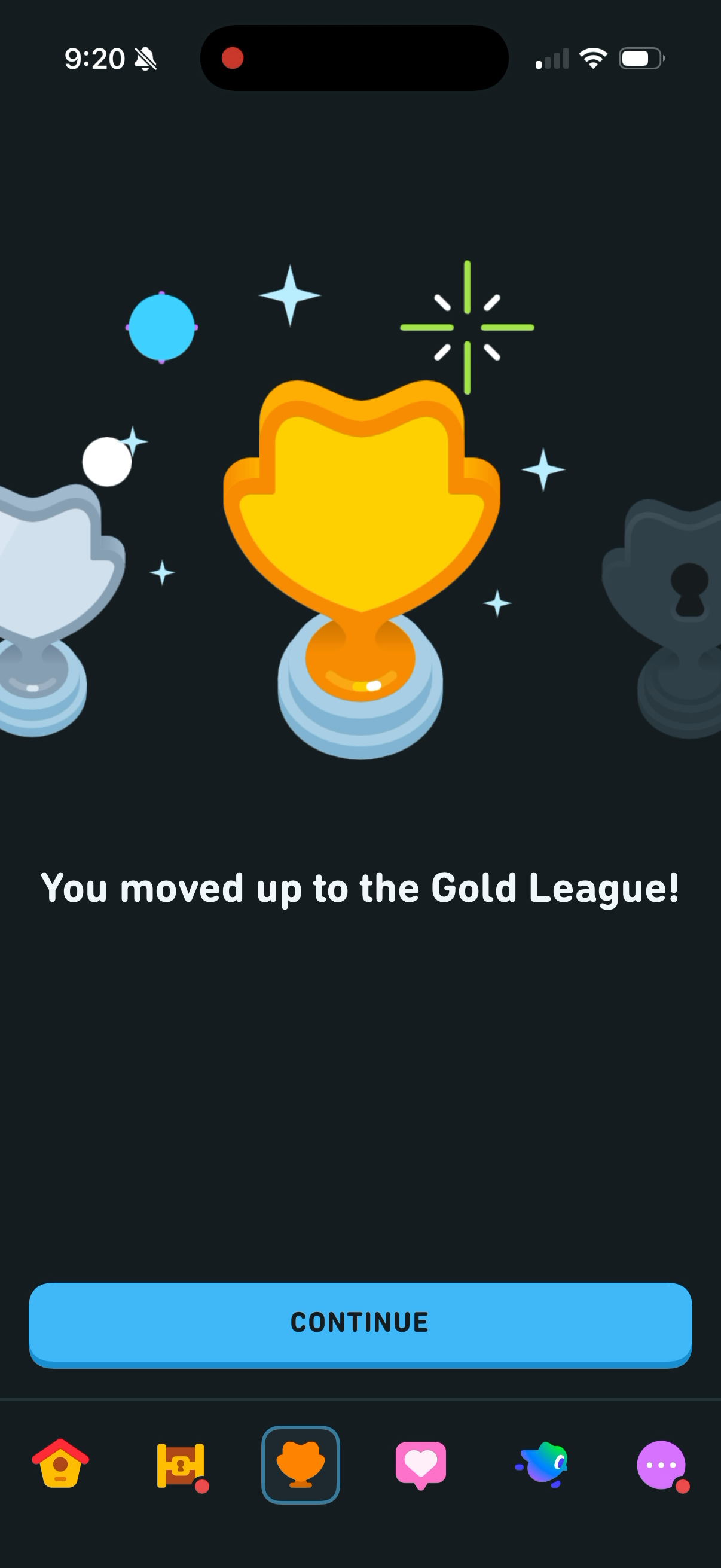 Promotion celebration screen with a gold trophy, the previous silver trophy faded to the left, and the next locked trophy faded to the right — caption "You moved up to the Gold League!"